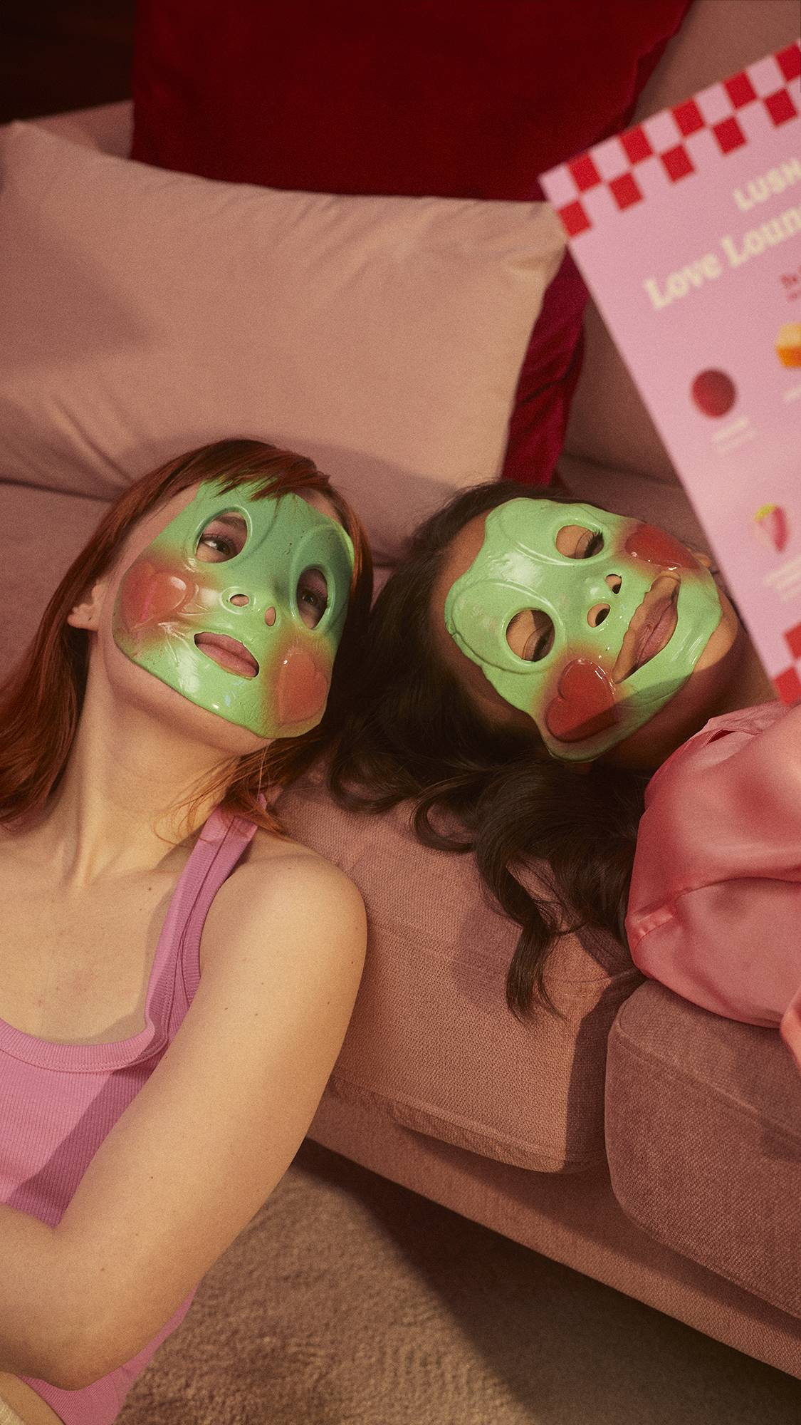 Two models are lying against a comfy sofa and are both wearing the Prince Charming face mask. 