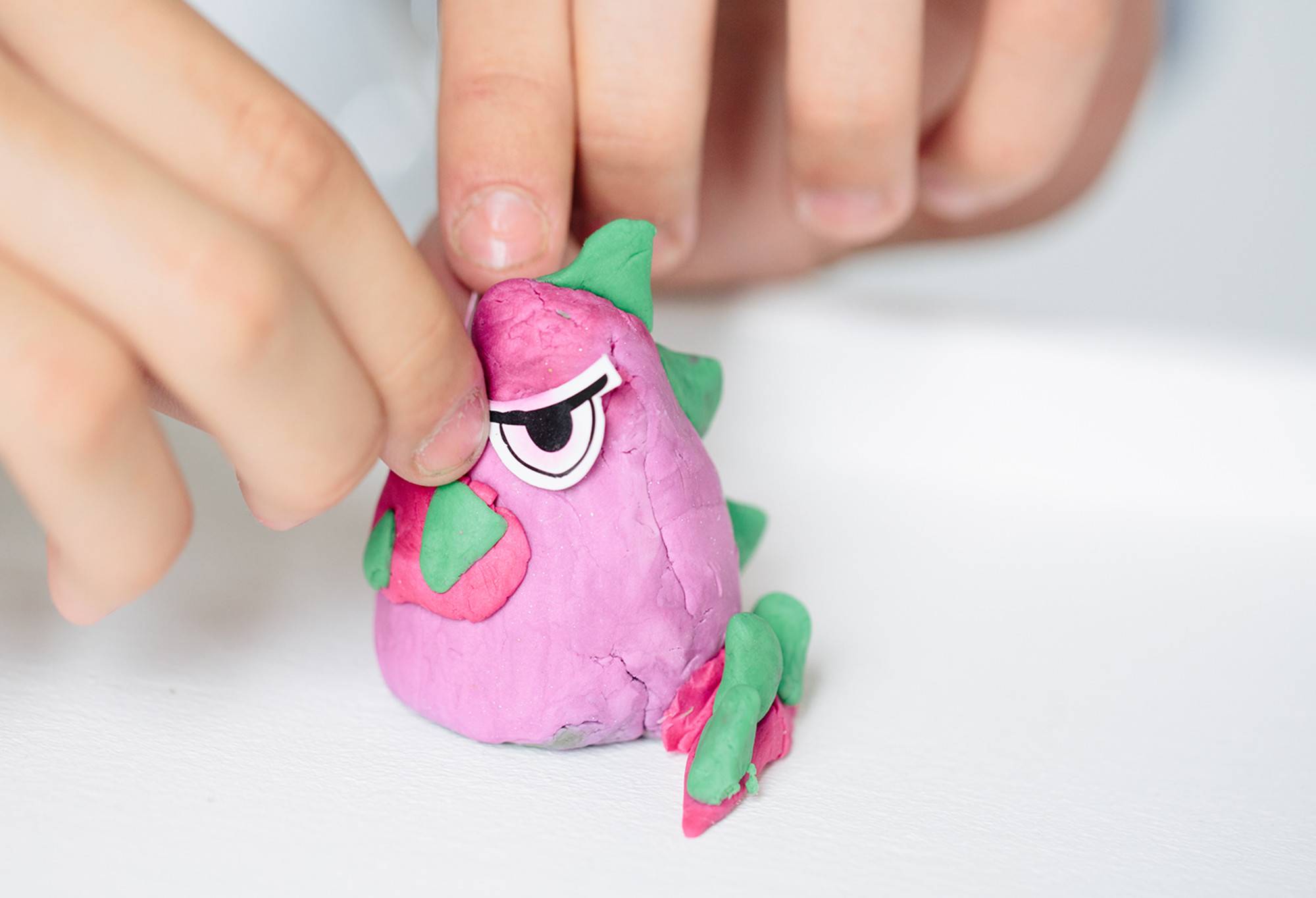 A pinky purple monster with green spikes along its back has been created out of Monsters & Aliens Fun, complete with paper eyes.