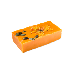 Pumpkin Spice. A rectangular block of bright orange soap topped with a pressed, dried yellow flower and a scatter of dark green pumpkin seeds.