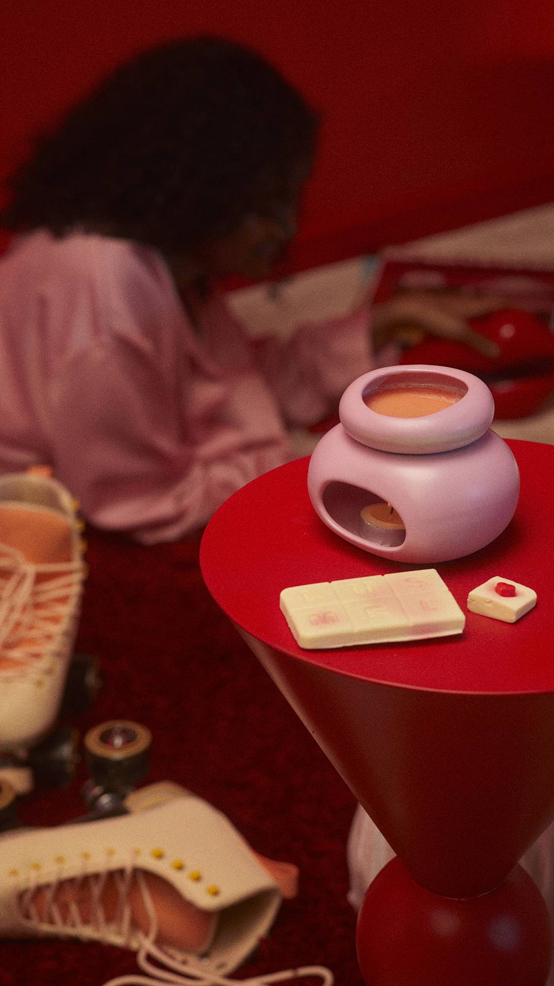 The Queen of Hearts product is melting in a pink wax burner on a red table. There are some roller skates just out of focus to the side. 