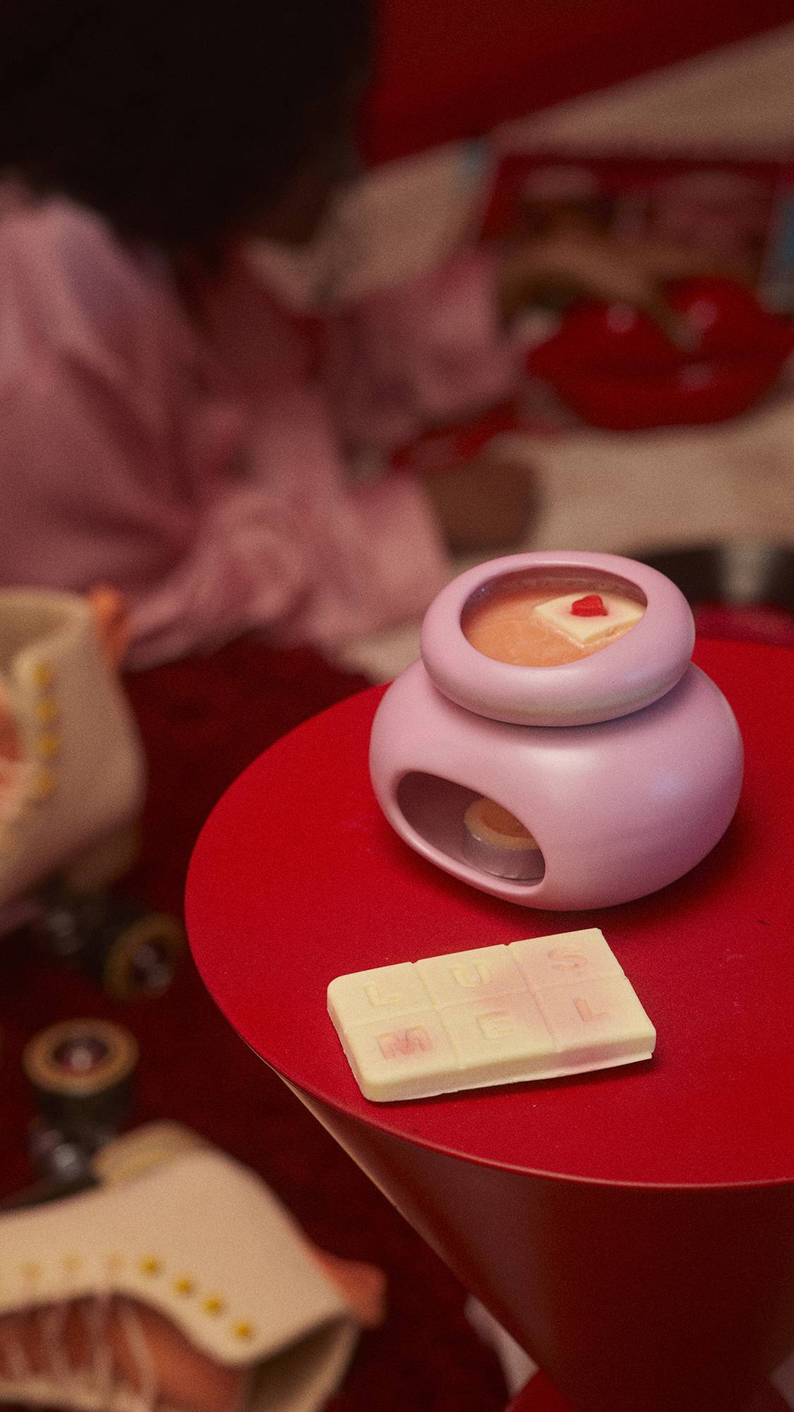 The Queen of Hearts product is melting in a pink wax burner on a red table. There are some roller skates just out of focus to the side. 