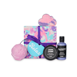 Relax. A square gift box wrapped in pastel blue, pink and purple marbled paper and a dark purple string surrounded by 4 LUSH products including a bath bomb, shower gel, bubble bar and lotion pot. 