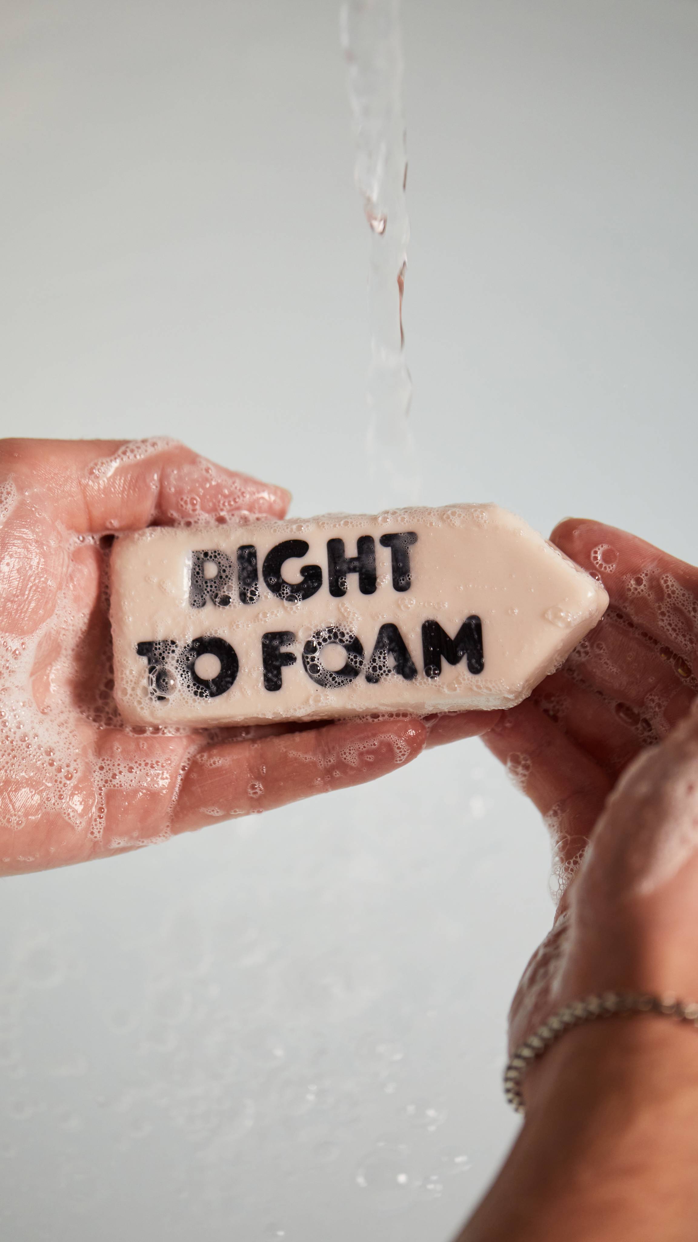 Image shows a close-up of the model's hands as they create a lather with the Right to Foam soap under running water.
