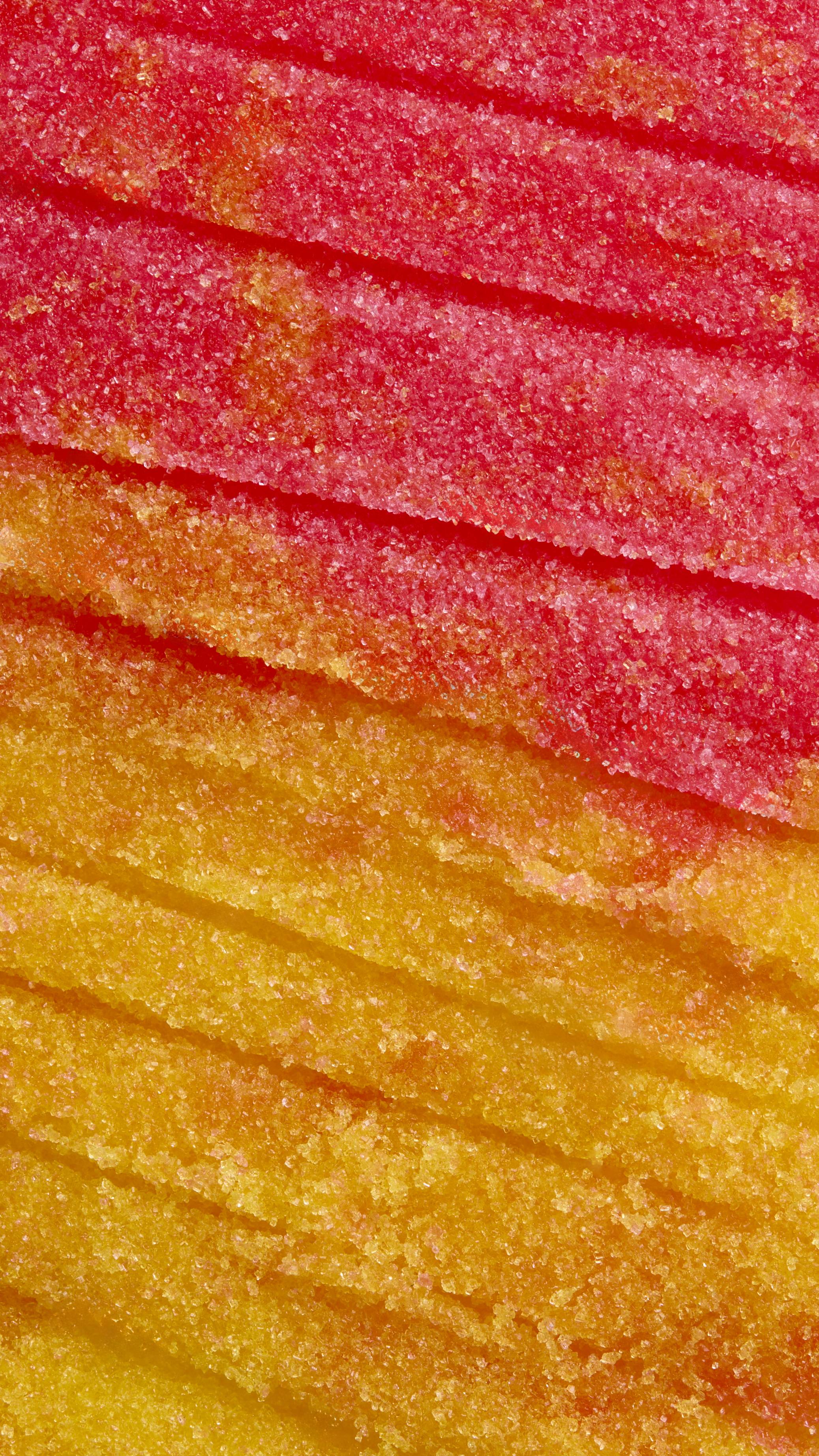 An extreme close-up shows the grainy, crystalline texture of the "Rub Rub And Custard" lip sugar scrub. Horizontal bands of vibrant pink and bright yellow sugar meet in the middle, creating a saturated, candy-like pattern of coarse granules.