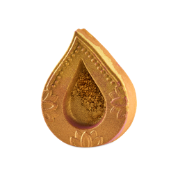 Saanjh. A teardrop-shaped golden Lush bath bomb designed like a diya lamp, featuring detailed embossed patterns around the rim and golden shimmer filling the central recessed well