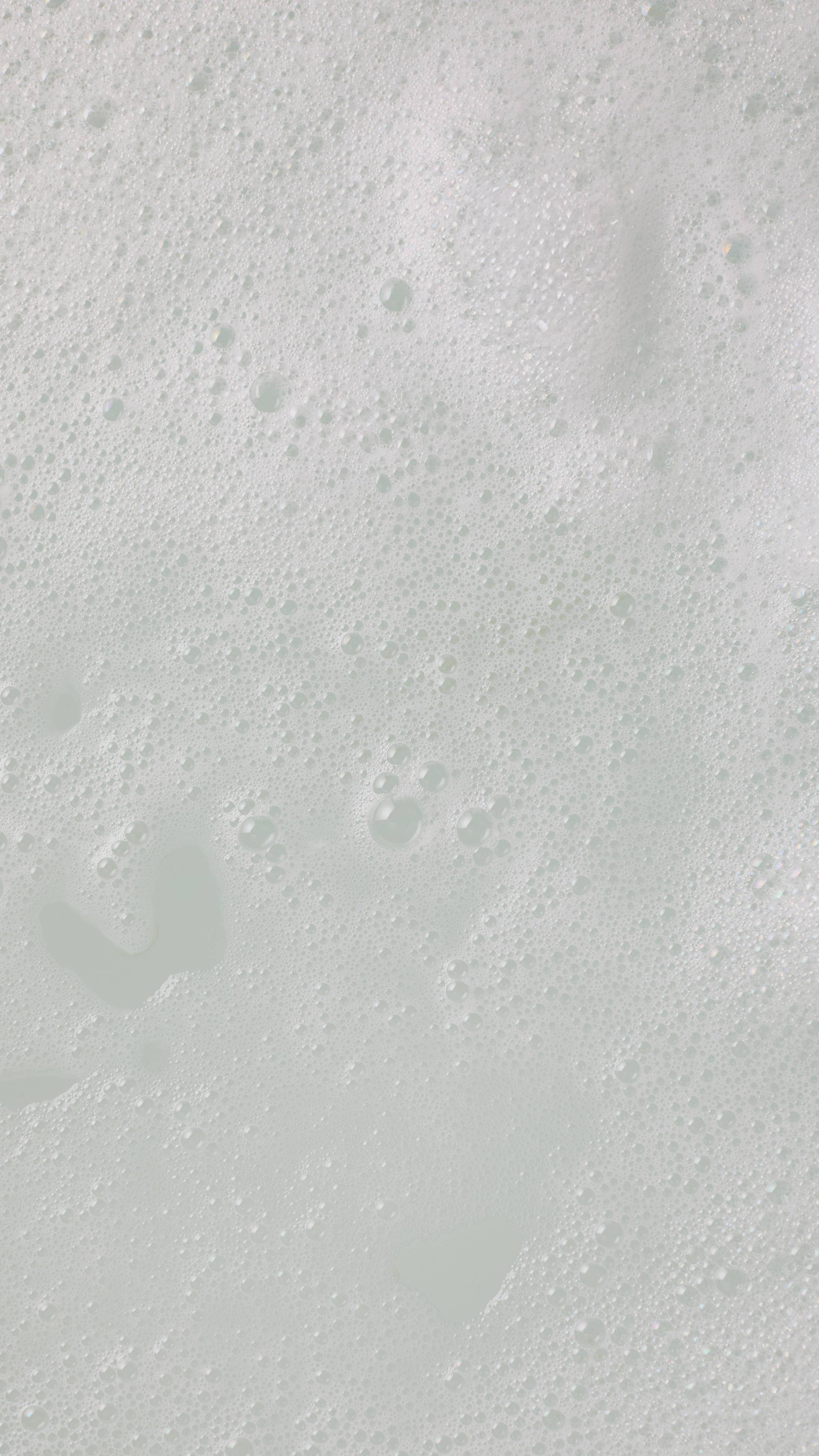 A close-up, aerial image of the bath water after using the Santa Moritz bubble bar. There is a blanket of thick, fat bubbles with creamy, soft bath water visible through a large gap.
