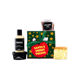 A Lush "Santa's Sweet Treats" gift box decorated with yellow stars and a green ribbon, surrounded by S'mores shower gel, Yuzu Cheesecake body butter, Christmas Pud shower jelly, and a soap.