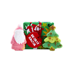 A Lush Secret Santa gift set featuring a green wrapped present with a red tag, flanked by a Santa Claus-shaped bath bomb and a green Christmas tree bath bomb.