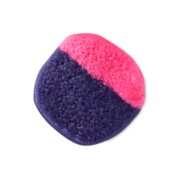 The square Sex Bomb Body Scrub features a two-tone design split diagonally between bright pink and deep purple, displaying a coarse, sugary texture against a light background.