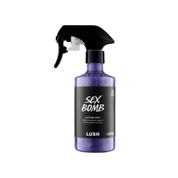 A bottle of purple Sex Bomb Glitter Mist with a black spray nozzle. The liquid swirls with shimmering plastic-free glitter.