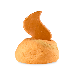 A rounded, solid Lush Bubble bar in a warm peach/tan color. Protruding from the top is a smooth, flame-shaped bath melt in a darker, glossy caramel/amber color. The product is the Shamash Bubble bar, set against a light grey background.
