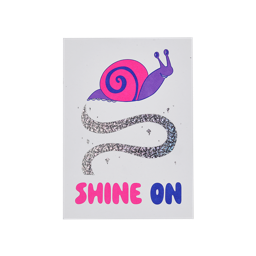 Shine On. A portrait A5 postcard. It has a white background with a large pink, purple and blue snail at the top leaving behind a swished line of glittery, silver "slime". The Words "SHINE ON" are printed in pink and blue at the bottom.