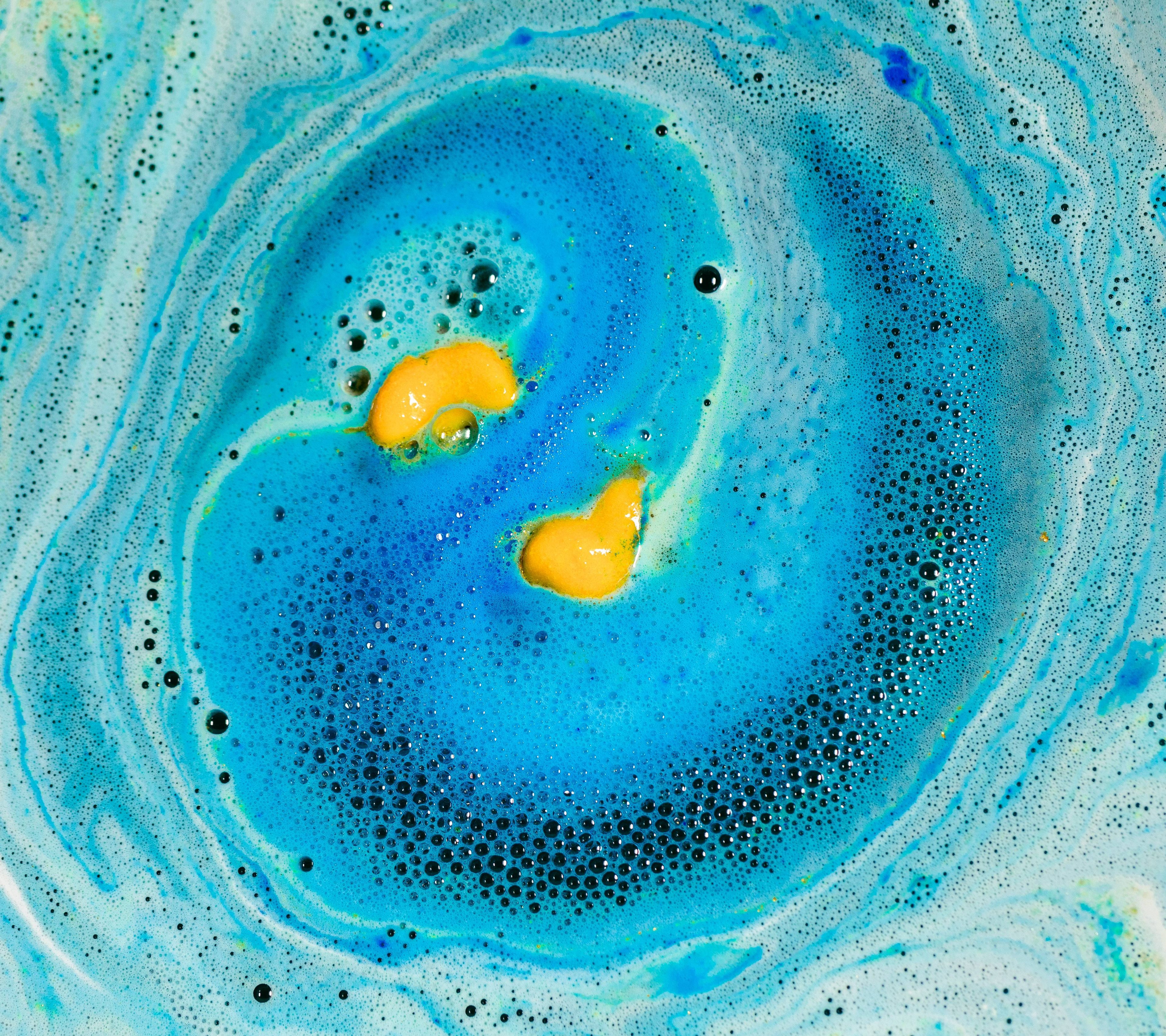 Image shows the Shoot for The Stars bath bomb mostly dissolved in a sea of swirling blue, leaving two chunks of golden stars. 