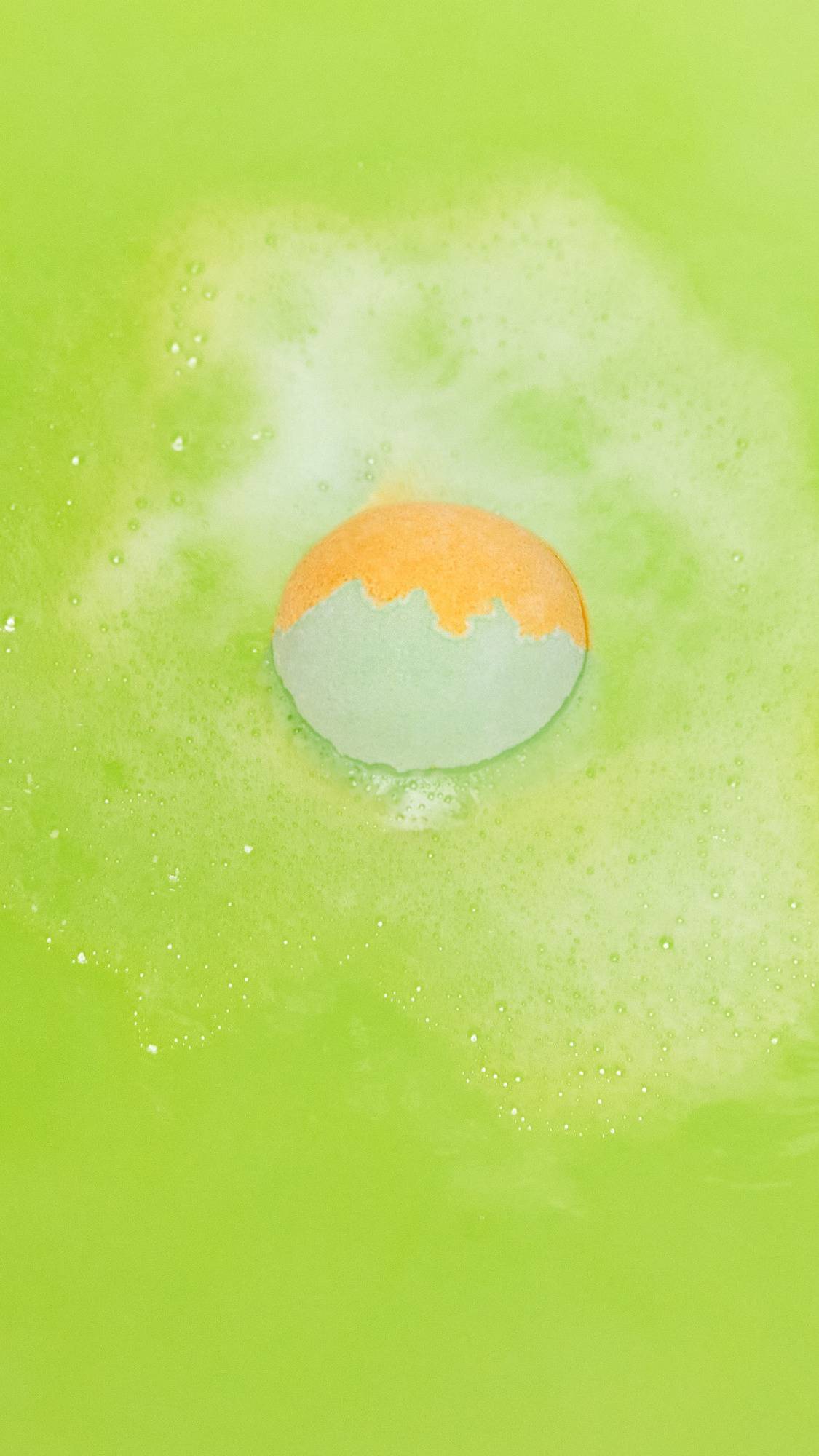 The Slammer bath bomb is sitting in the bath slowly dissolving, leaving behind a vivid, lime-green sea of water. 
