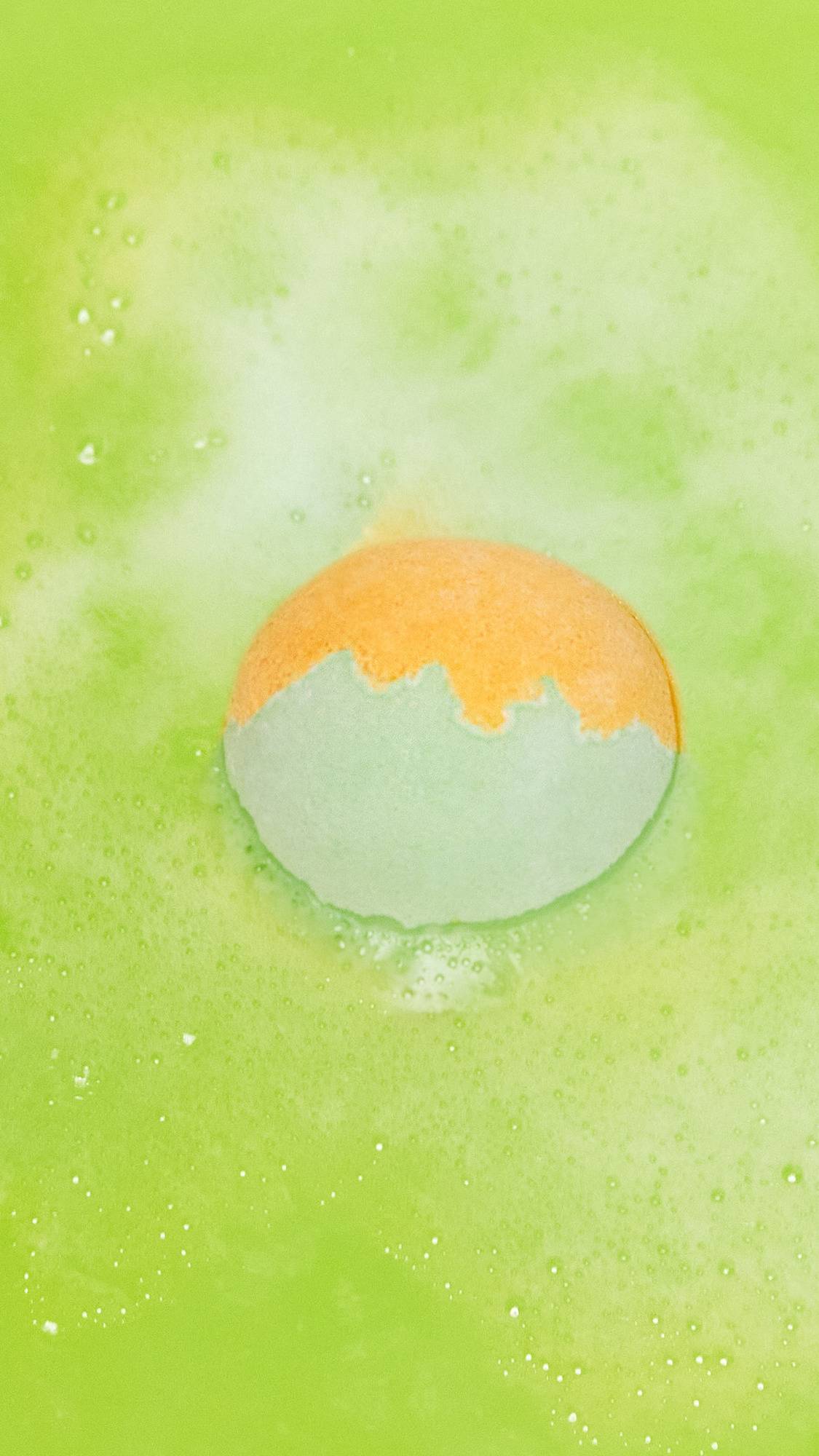The Slammer bath bomb is sitting in the bath slowly dissolving, leaving behind a vivid, lime-green sea of water. 