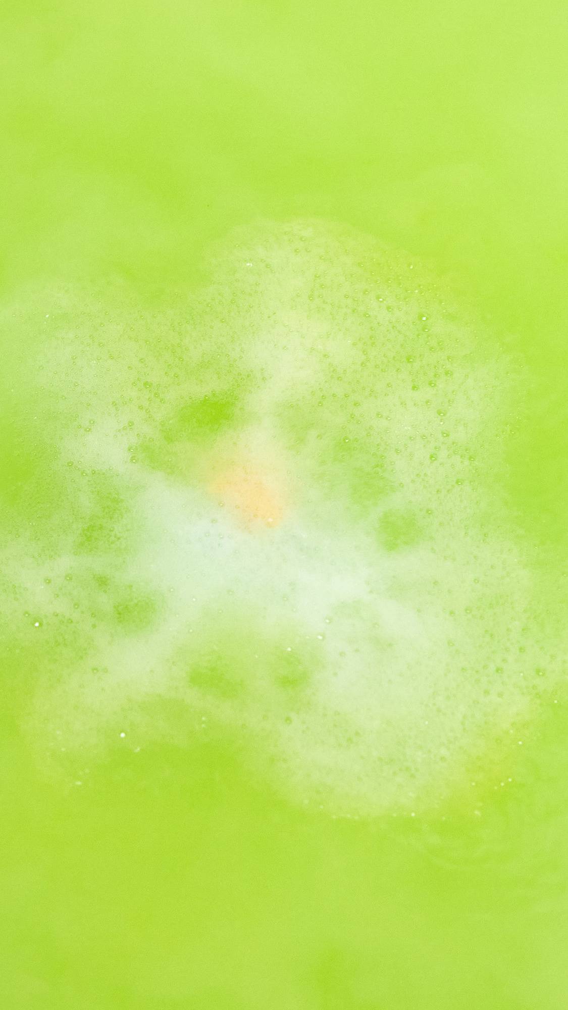 The Slammer bath bomb is slowly dissolving, leaving behind a vivid, lime-green sea of water. 