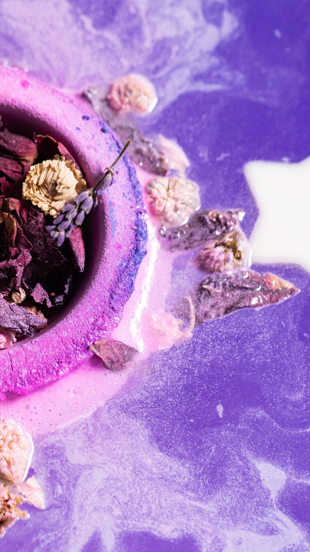 A pink bombshell exploding with petals in purple fizzy water.
