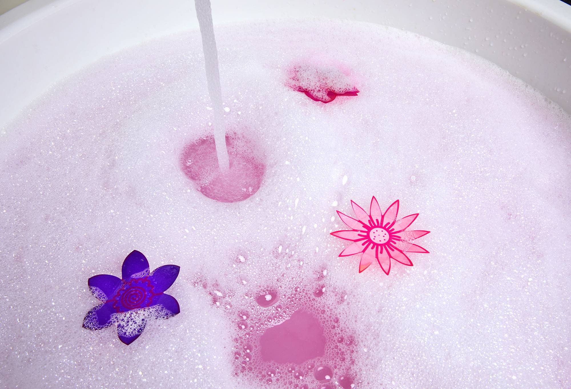 Image shows a bath full of pale pink water, covered in foamy bubbles with the paper flowers floating atop.