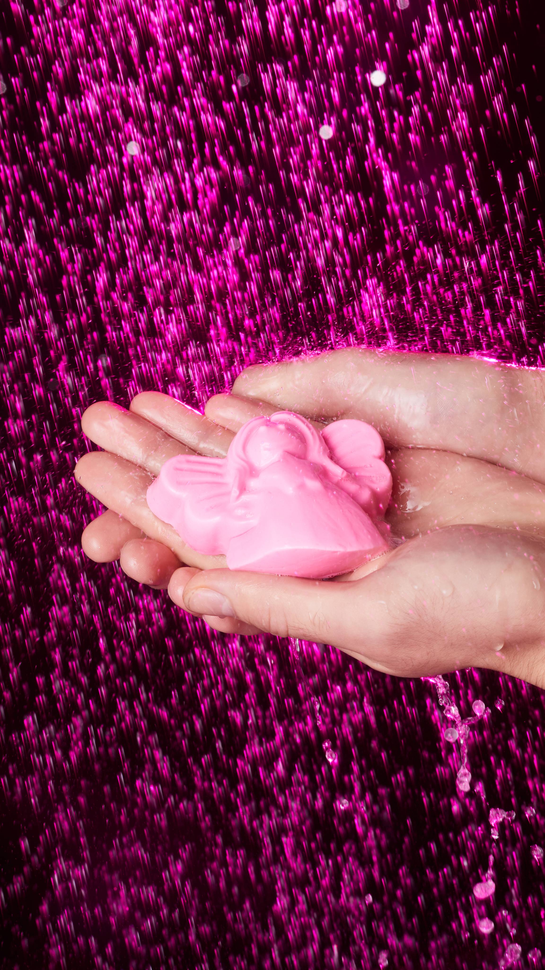 Image shows a close-up of the model's hands cupping the Snow Fairy shower jelly gently under shower water. 