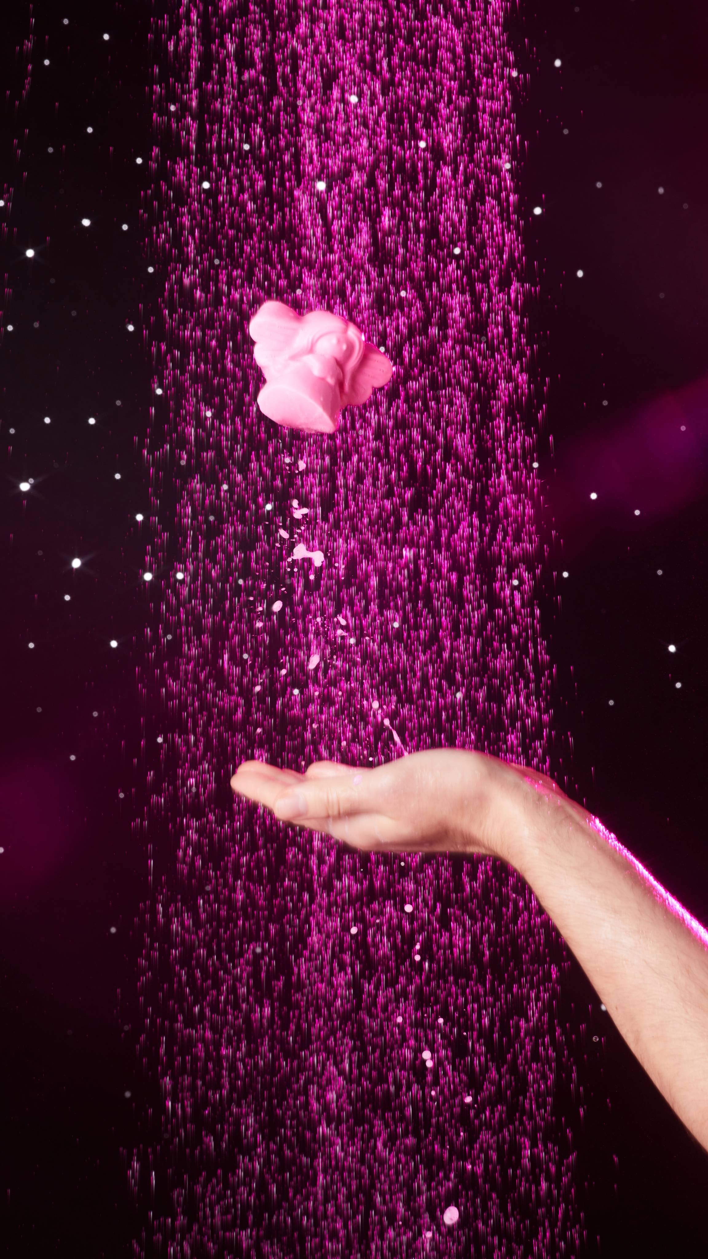 Image shows a close-up of the model's hand in the shower having just thrown the Snow Fairy shower jelly in the air. 