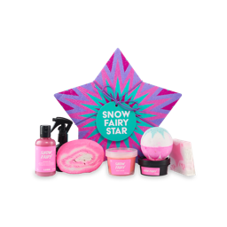 Snow Fairy Star. A five-pointed strap-shaped gift box with radiating star design in pink, purple and blue, tied with a purple string and gift tag. Seven Lush Snow Fairy-themed products sit in front of the gift box. 