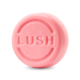 Snow Fairy. A round, pastel pink solid shampoo bar embossed with the word "LUSH" in central capital letters inside a circular groove