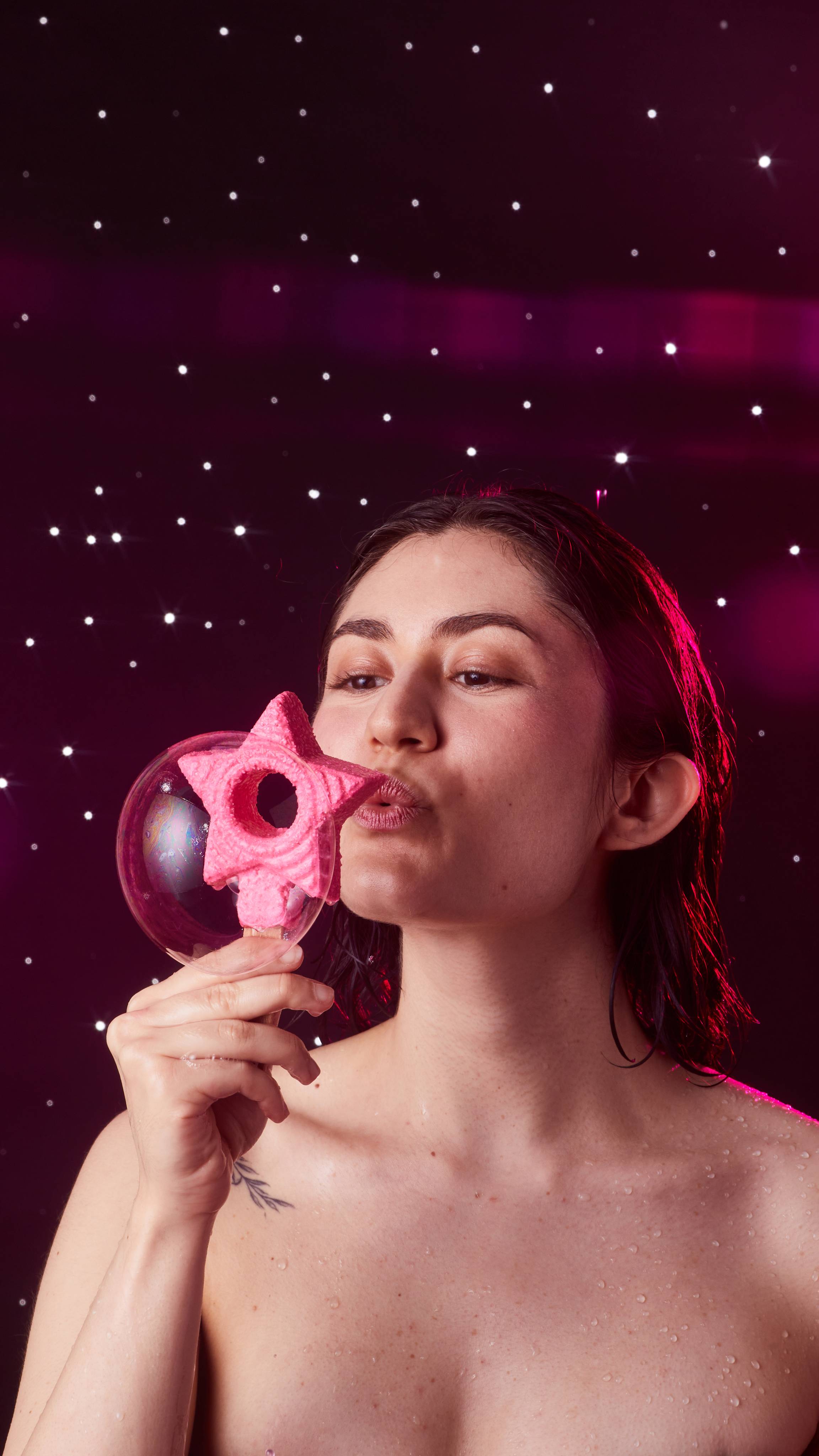Image shows the model holding the Snow Fairy wand up to their face as they blow a big bubble out of the star hole. 