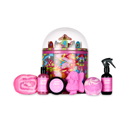 Snow Fairy’s Magical Wonderland. A round, mental-tin gift box decorated with retro mushrooms and groovy designs. The lid has a clear dome with protruding mushrooms inside. There are six Lush Snow-Fairy-themed products surrounding it. 