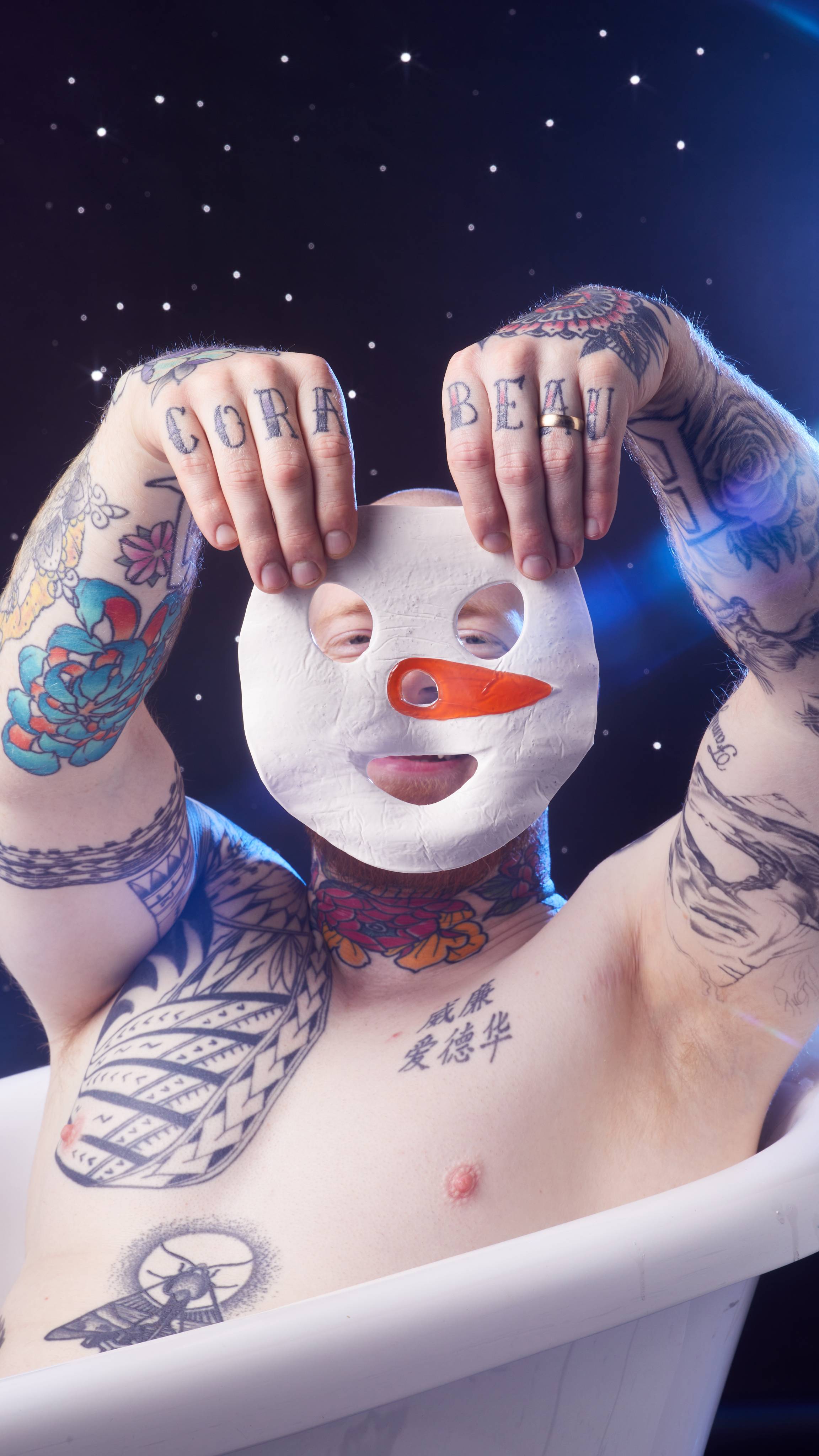 A starry background as the model holds up the Snowman sheet mask up to cover their smiling face from the camera. 