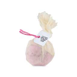 Softening Marshmallow And Rose Cataplasm. A pink, spherical bath bomb wrapped in muslin fabric, tied with a knot and pink string and product tag which reads "Don't unwrap, dunk this in your bath"