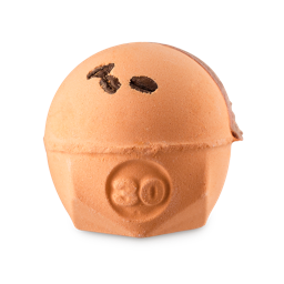 Sonic Death Monkey. A spherical bath bomb with a flat, geometric base. The product is a warm, orange colour with the number "30" embossed on the side, three coffee beans embedded on top and a milk chocolate-coloured drizzle of solid oil. 