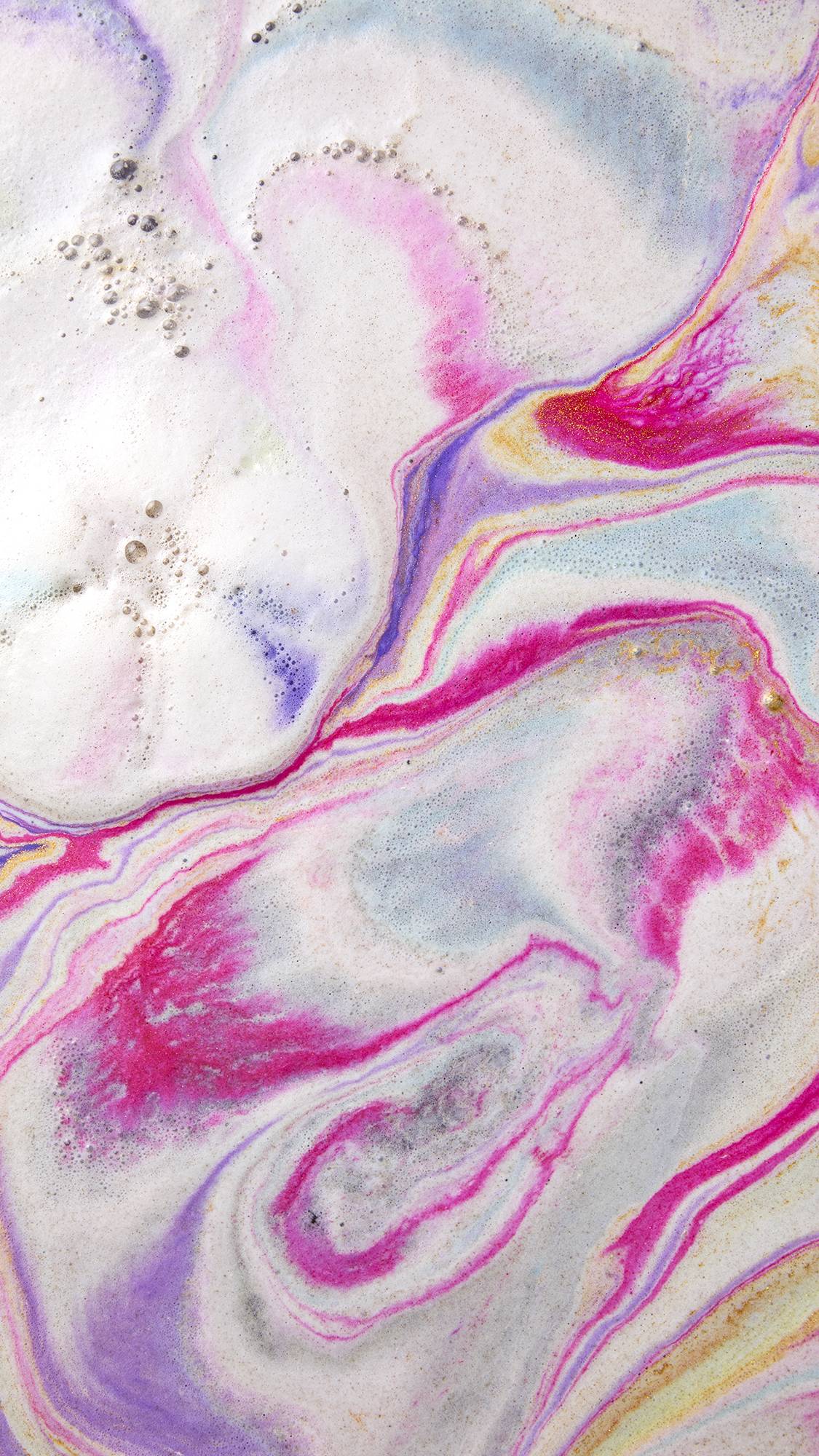 The image shows swirling bath art from the goldenStar of Wonder product, a dreamy blend of pastel pink, purple, and blue hues. Intricate marbled patterns with golden shimmer mix with white foam across the water surface.