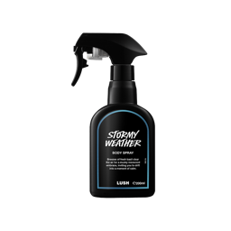 A recycled black plastic LUSH body spray bottle with a trigger nozzle stands upright with a deep blue rimmed label with white text that reads "Stormy Weather Body Spray".