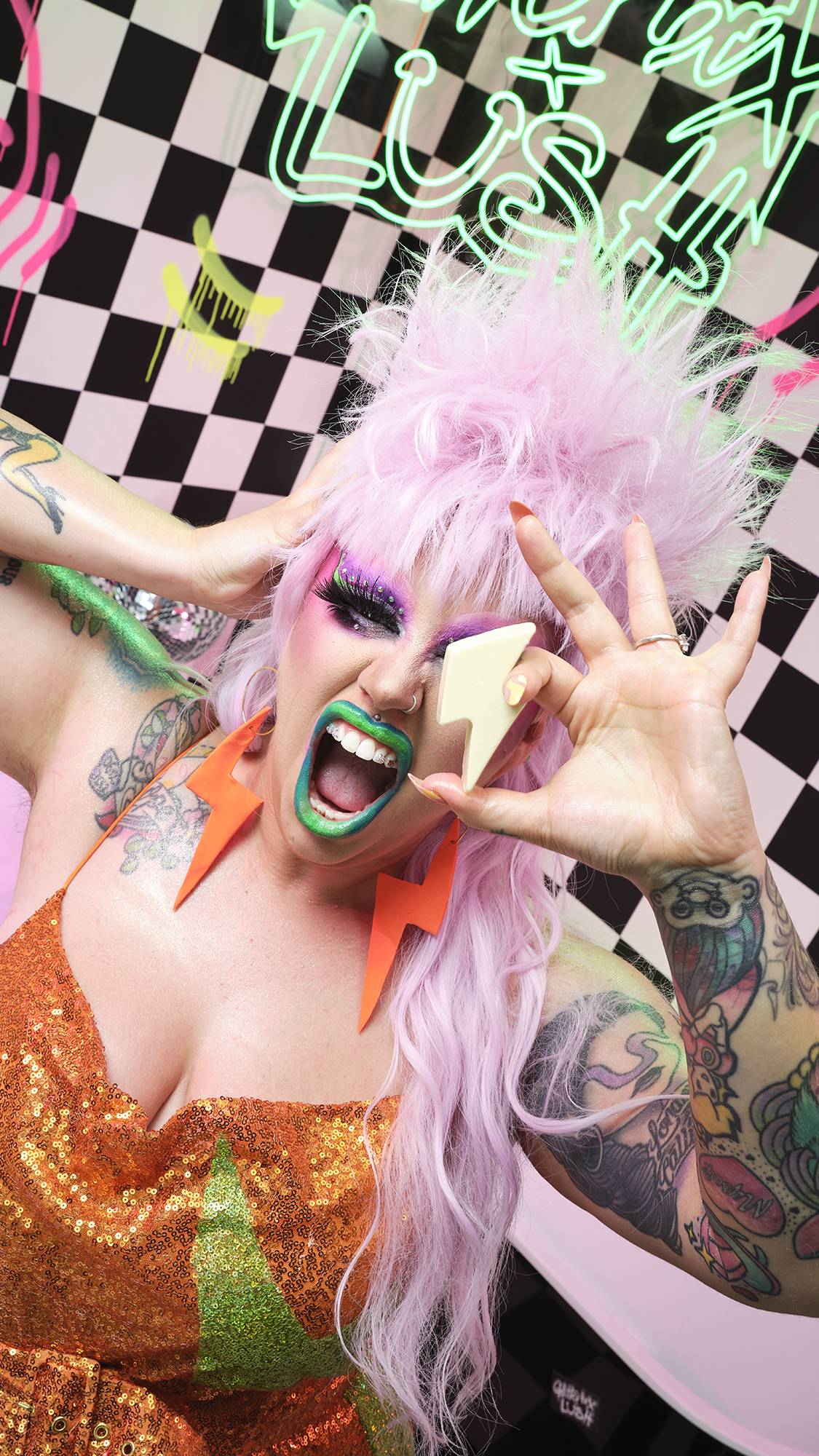 Model holds the bolt-shaped bar in front of their face. They're wearing bold colours on a checkered and graffiti background.
