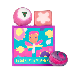 Sugar Plum Fairy. A square gift box decorated with a brightly coloured fairy in a hand-drawn style and the words "Sugar Plum Fairy" across the bottom. There are three, pink Christmas Lush products sitting around the box. 
