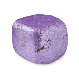 Sugared Plum. A solid facial sugar scrub. The product is a deep purple colour and has been shaped to resemble a soft, rounded cube. There is a coating of purple/silver lustre across the surface of the product. 