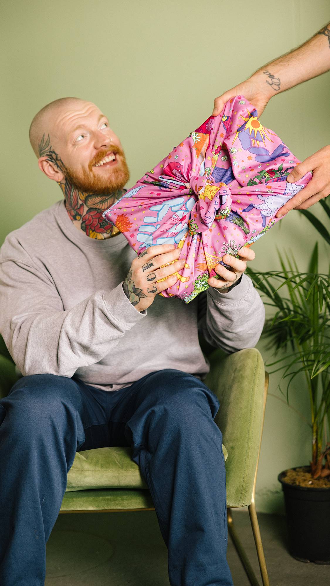 Image shows model being given a gift, neatly wrapped in the Summer Solstice knot wrap showing glimpses of detailed design.