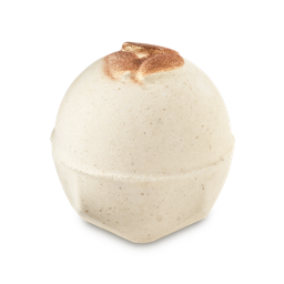 Super Milk. A spherical, off-white bath bomb with a speckled texture and flat, geometric base. The top features three embossed, decorative, shimmering bronze almonds.