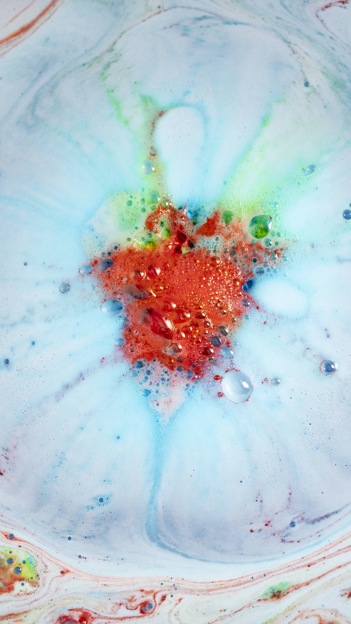 The Super Dad bath bomb has fully dissolved leaving a sea of thick blue foam with a bright flash of contrasting ruby-red burst in the centre.