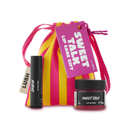 Sweet Talk. A yellow and pink-striped fabric pouch with a pull-tie top and pink tag. A small glass pot of Sweet Talk lip scrub and a tube of Crush lip balm sit in front of the gift bag. 