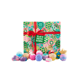 The Art Of Christmas Bathing. A large, square gift box designed with layered illustrations of vibrant baubles and gold detailing, tied with a red ribbon and gift tag. Fifteen bath bombs and bubble bars sit in front of the box. 