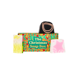 The Christmas Soap Box. A rectangular cardboard gift box designed with red, yellow and green festive patterns and gold text. Three Christmas soaps sit around the box. 