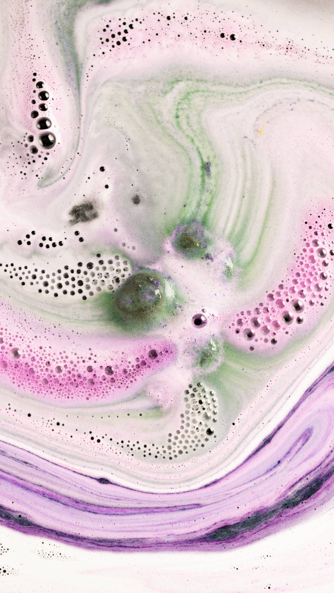 The Cloud bath bomb has almost fully dissolved surrounded by bright pink and deep green mesmerising swirls. 