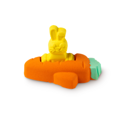 The Flying Carrot, a little yellow bunny bath bomb sits inside an orange carrot bath bomb that's in the shape of a plane.