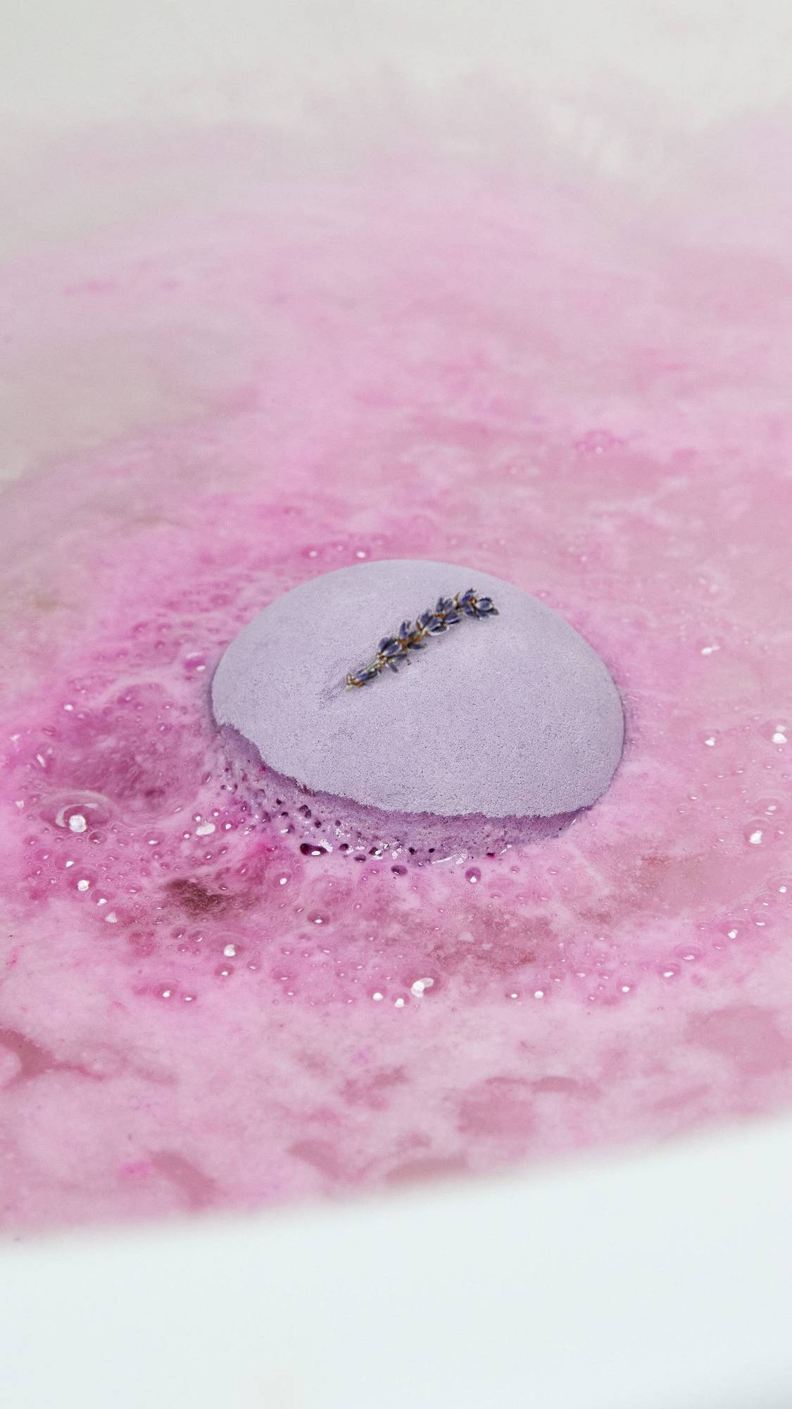 The One With Lavender bath bomb has been placed gently into the bath as it begins to push out a thick blanket of velvety, violet foam.