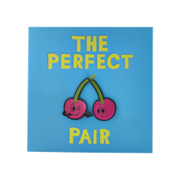 The Perfect Pair. A Square, sky blue gift card. Yellow text in the centre ready "The Perfect Pair" with an illustration of a pair of smiling cherries. The two cherries are also removable pin badges.