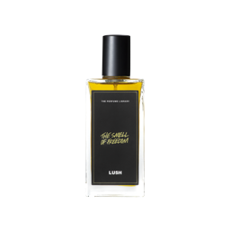 A glass perfume bottle filled with amber liquid. A black label reads 'The Perfume Library' and 'The Smell of Freedom'.