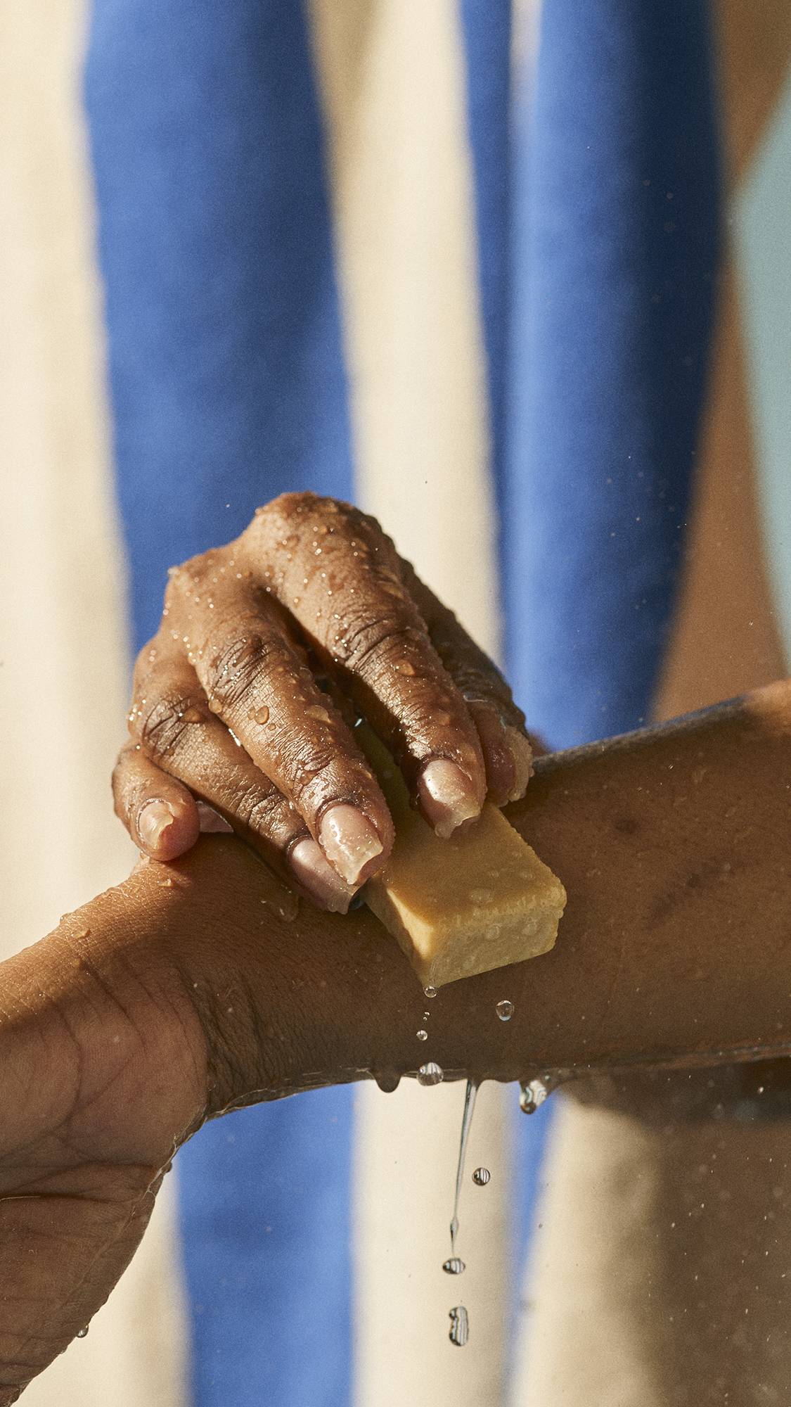 A close-up of the model’s hands and arms as they glide the sunblock over their skin.
