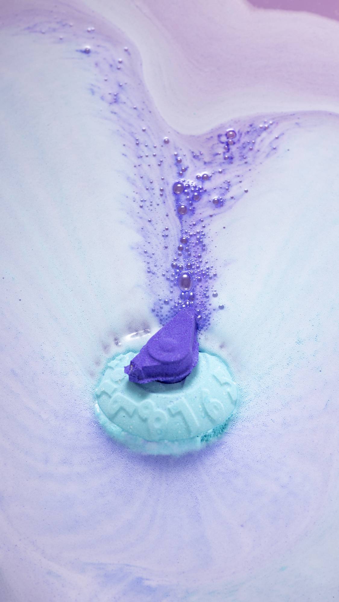 The Time To Relax bath bomb is dissolving leaving foamy swirls of blue and purple. 