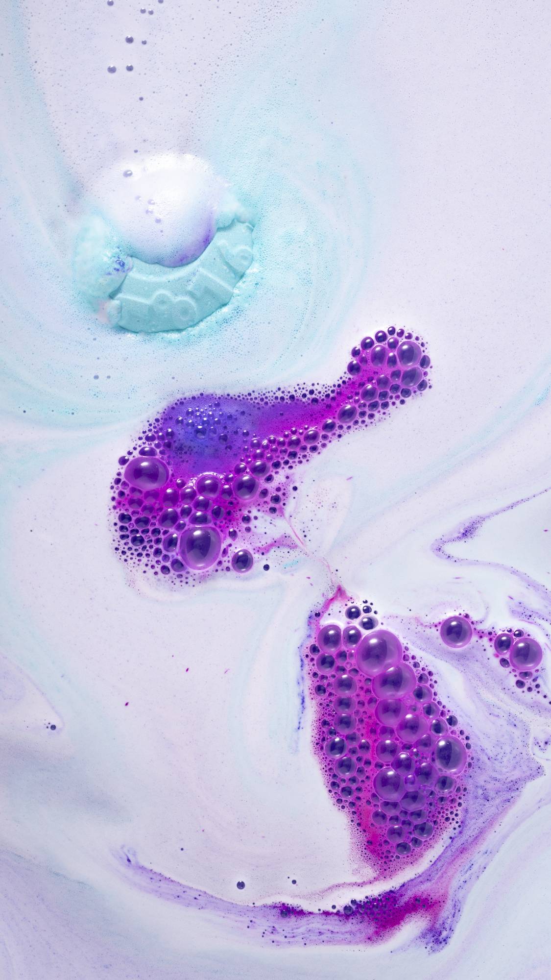 The bath bomb is dissolving leaving behind a galaxy of blue, pink and purple swirls. 